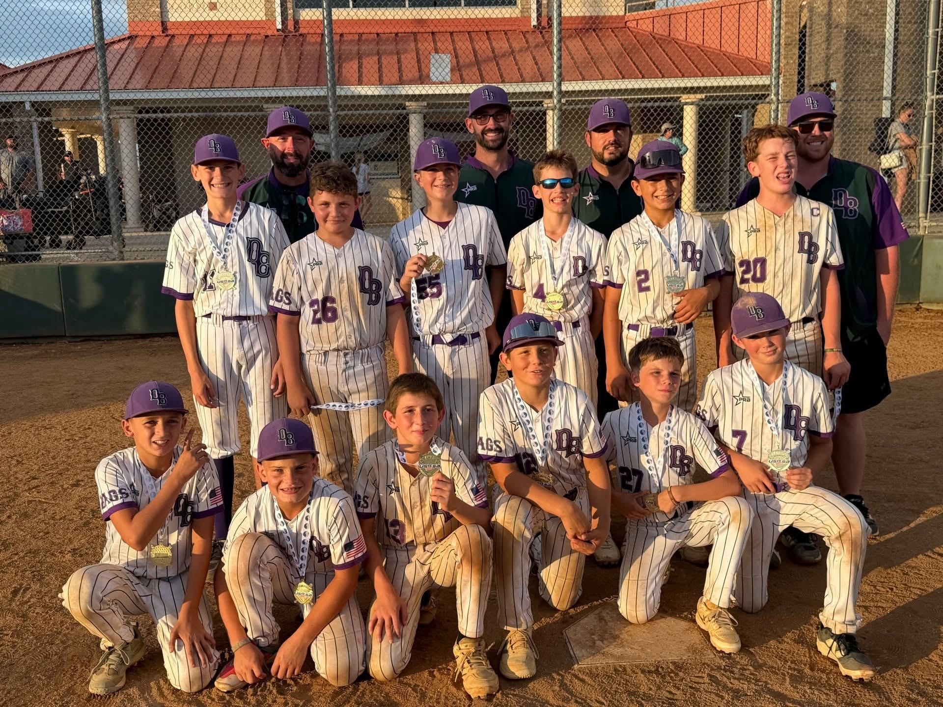 Dirtbags team in white pinstriped uniforms posing with medals at sunset